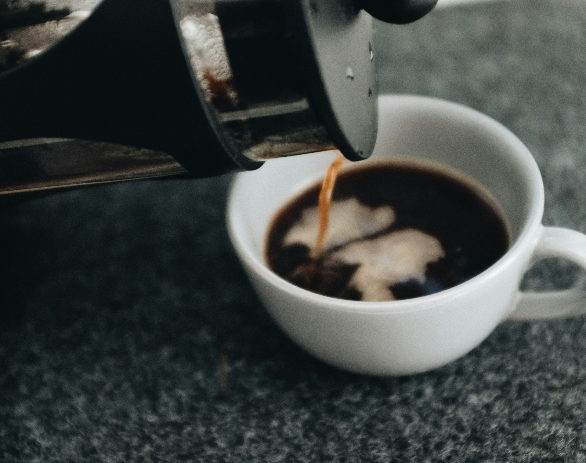 Coffee being poured from a French press into a white cup
